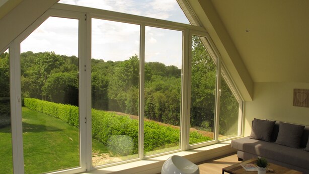 A modern living room with a large glass door leading to a lush garden. - La Garonde (Berthen)
