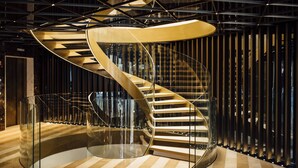 A modern spiral staircase with glass railings and a geometric ceiling design. - Almanac Barcelona (Barcelona)