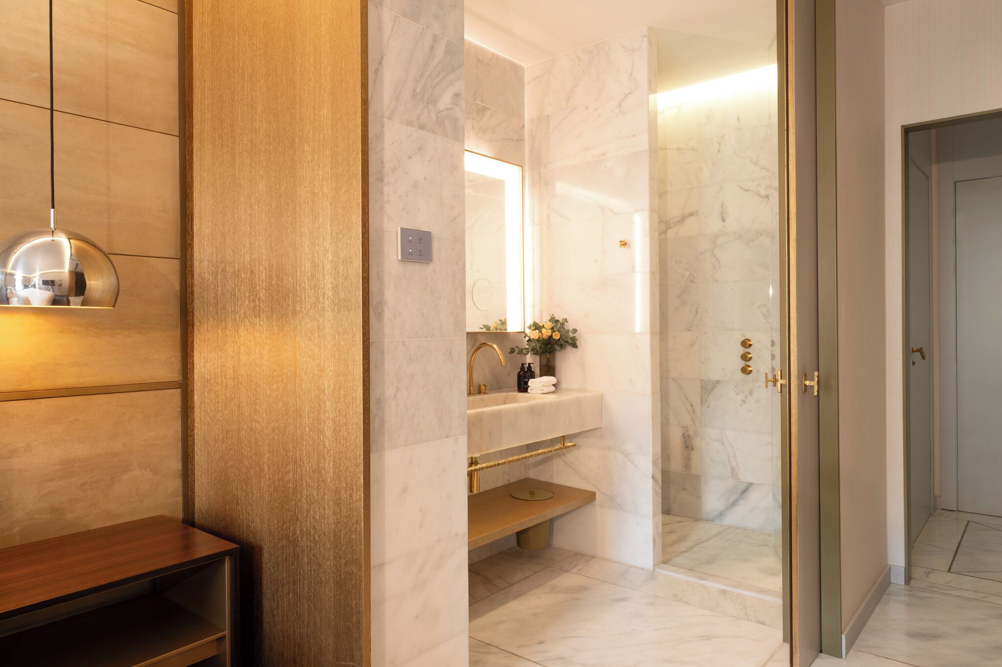 Une salle de bain moderne avec un meuble-lavabo en marbre, une cabine de douche en verre et un banc en bois.