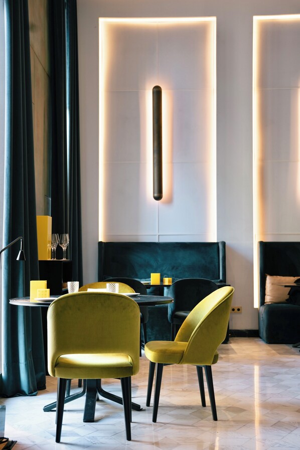 A modern dining area with two yellow chairs, a table, and a dark-colored sofa.