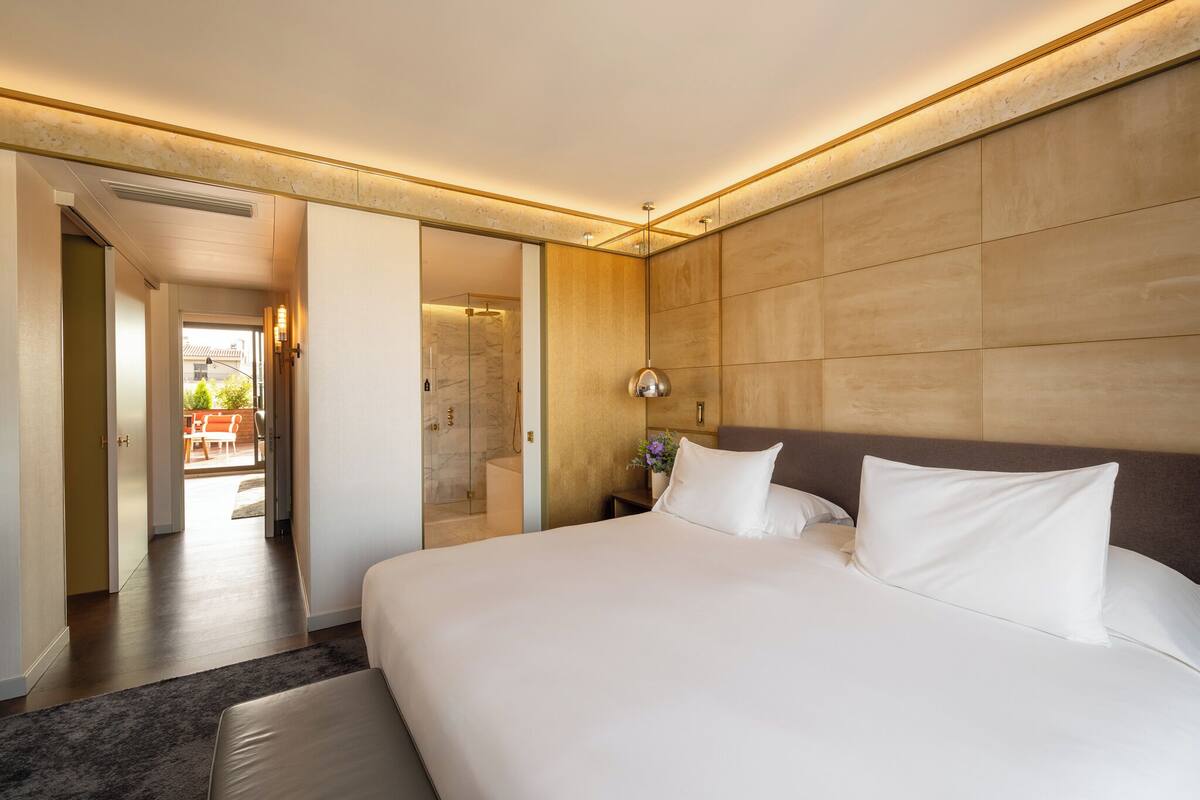 A modern hotel room with a large bed, a walk-in closet, and a view of the outdoor patio.