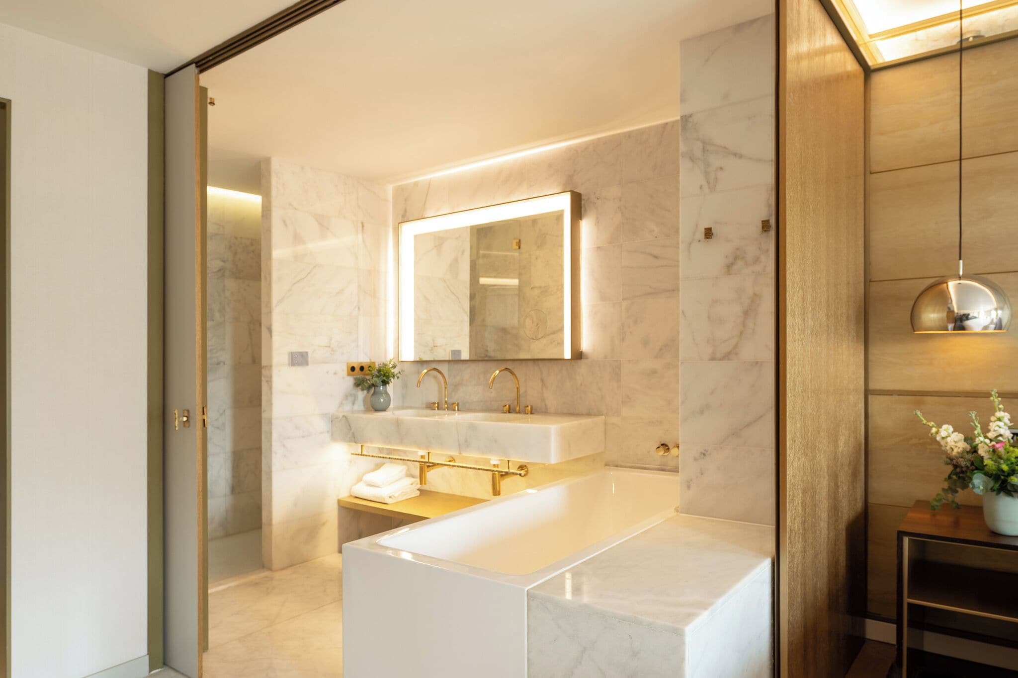 A modern bathroom with a large mirror, two sinks, and a bathtub.