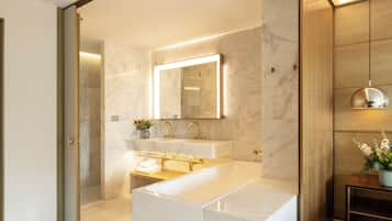 A modern bathroom with a large mirror, two sinks, and a bathtub.