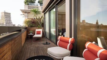 A modern balcony with wooden flooring, a small table with a chair, and a fire pit.