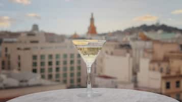 A martini glass on a marble table with a cityscape in the background.
