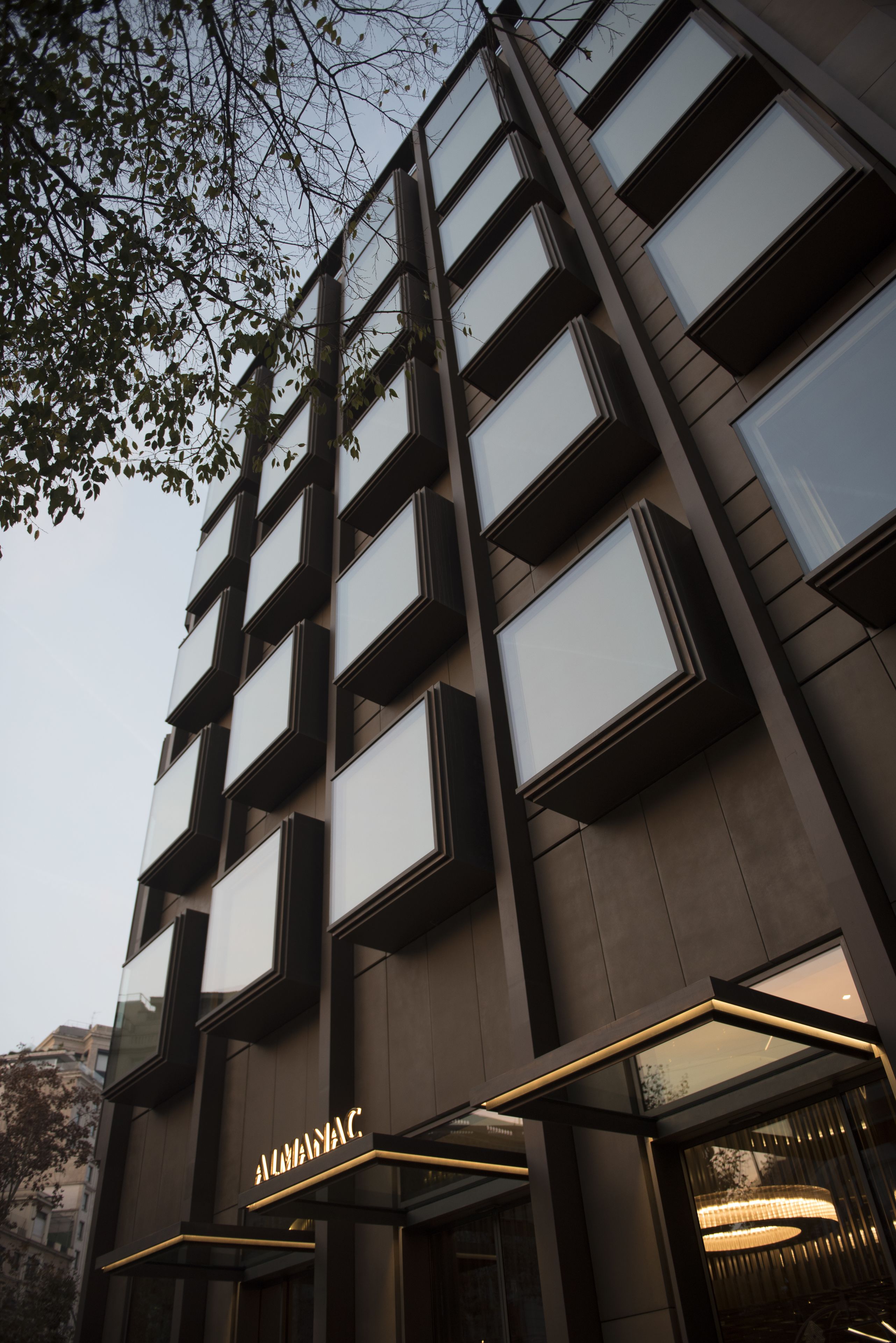A modern building with multiple balconies and a prominent entrance with a sign.