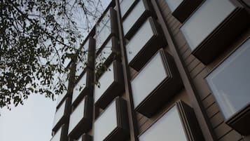 Un edificio moderno con varios balcones y una entrada destacada con un letrero.