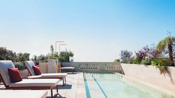 Een buitenzwembad, parasols bij het zwembad en ligstoelen