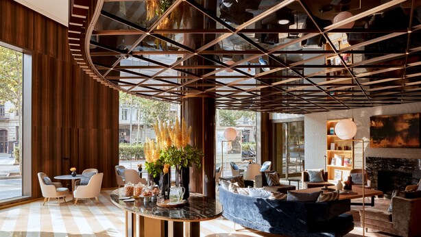 A modern lobby with a central round table, seating area, and a fireplace. - Almanac Barcelona (Barcelona)