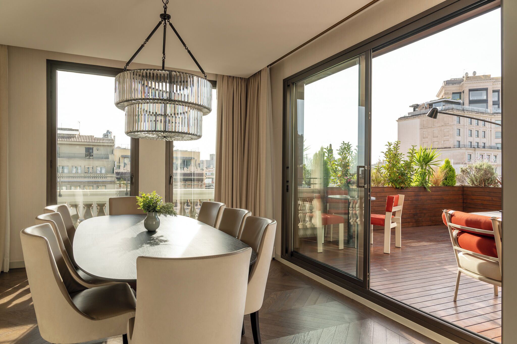 A modern dining area with a round table, chairs, and a hanging light fixture.