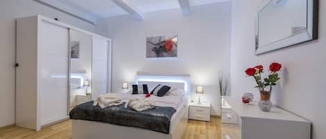 A modern bedroom with a bed, bedside tables, a wardrobe, and a mirror.