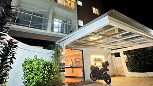 Een modern hotel met een overdekte parkeerplaats en een motorfiets ervoor geparkeerd.