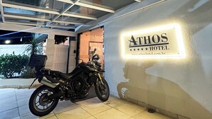 Een motorfiets geparkeerd in een overdekte parkeerruimte, met een bordje voor Hotel Athos.
