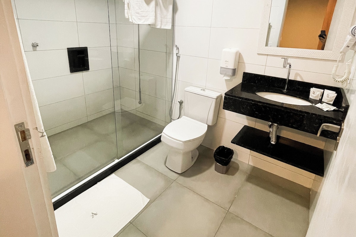 A modern bathroom with a glass-enclosed shower, a toilet, and a sink with a mirror above it.