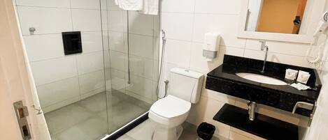 A modern bathroom with a glass-enclosed shower, a toilet, and a sink with a mirror above it.