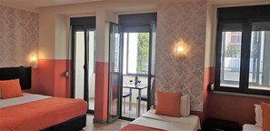 Une chambre d’hôtel avec deux lits, un balcon doté d’une table et de chaises, et une vue sur l’extérieur.