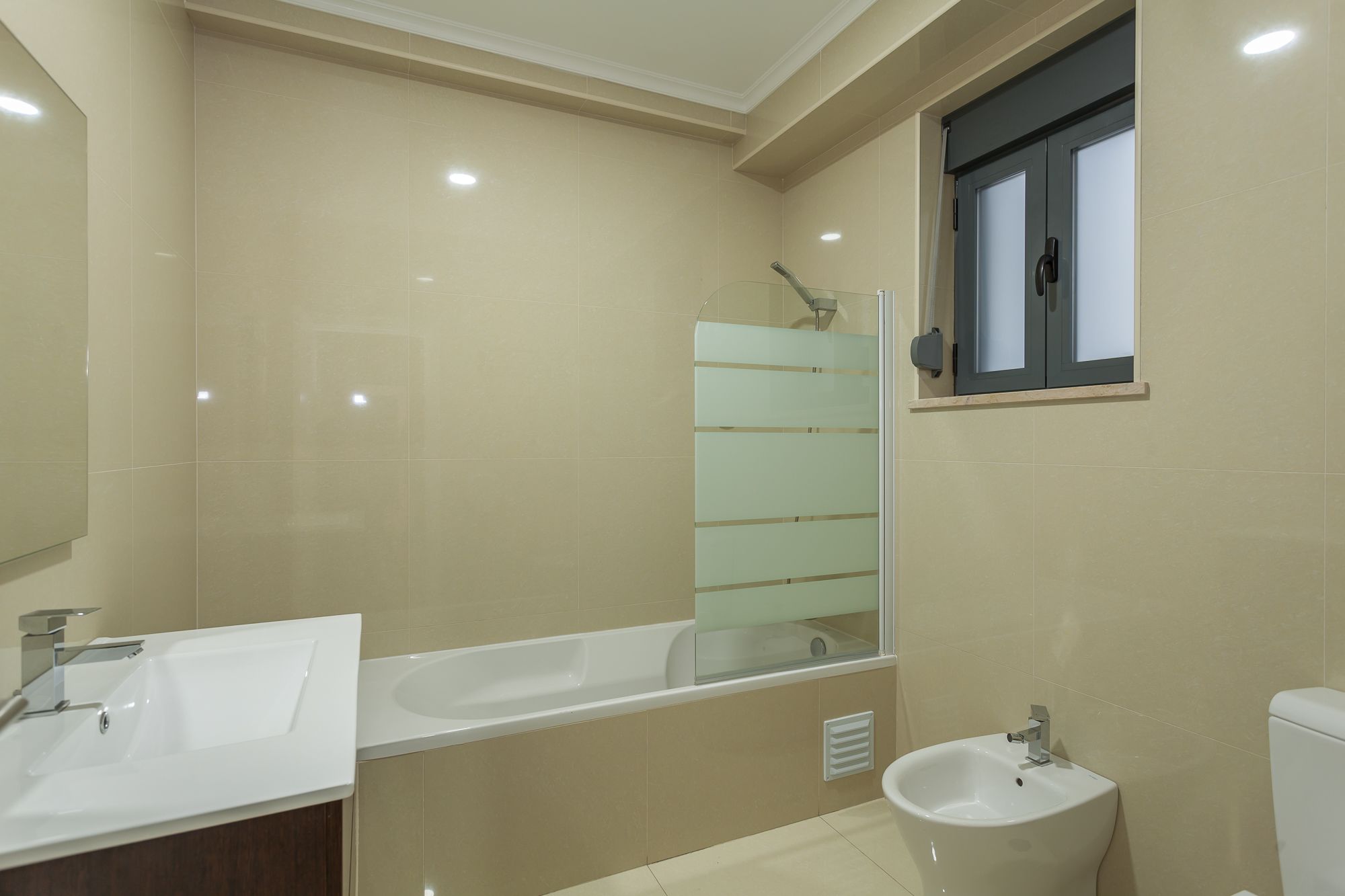 A modern bathroom with a bathtub, a sink, and a bidet.