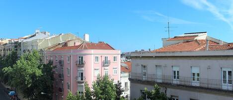 A row of multi-story buildings with balconies and a clear blue sky.