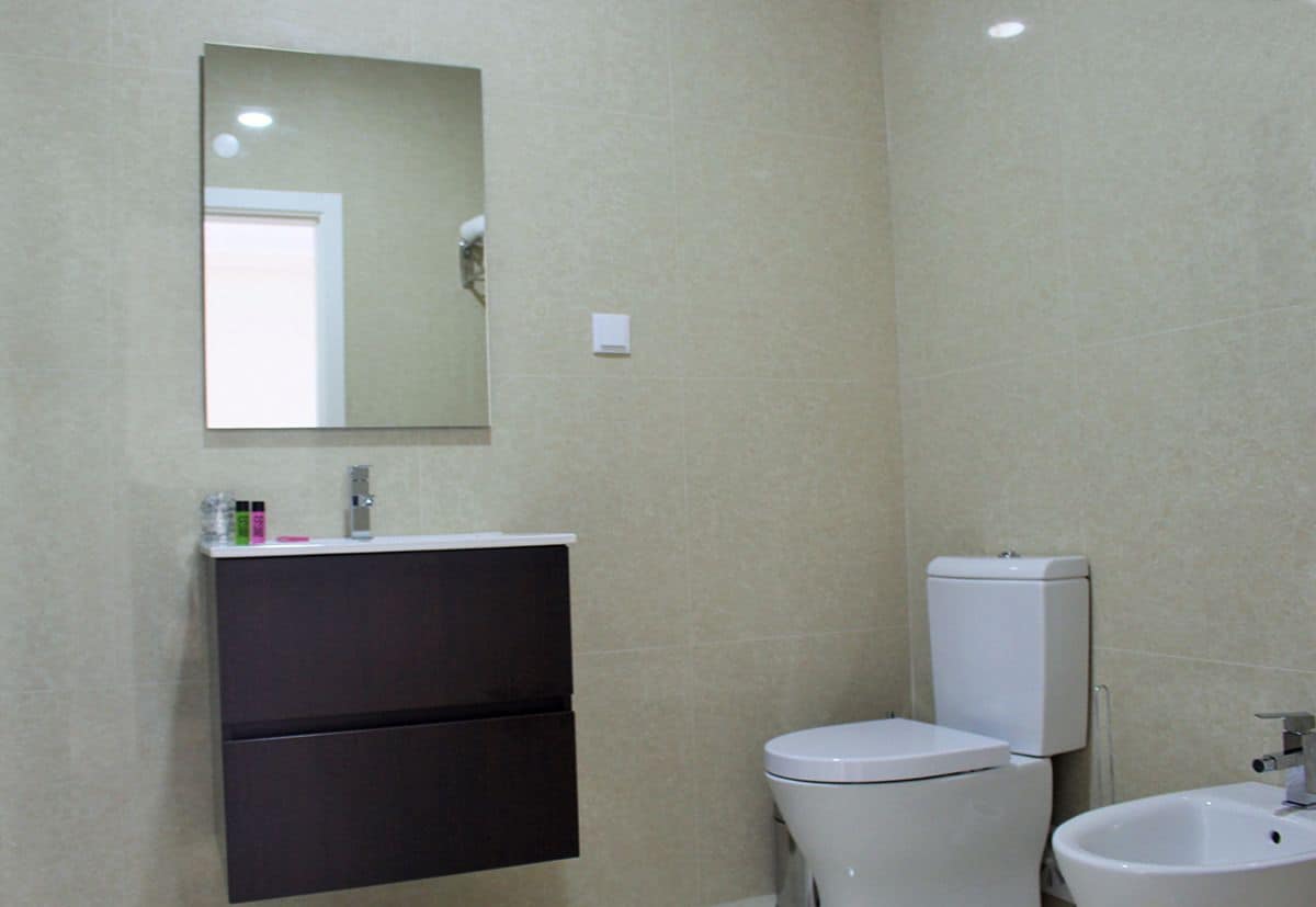 A bathroom with a toilet, bidet, and a mirror above the sink.