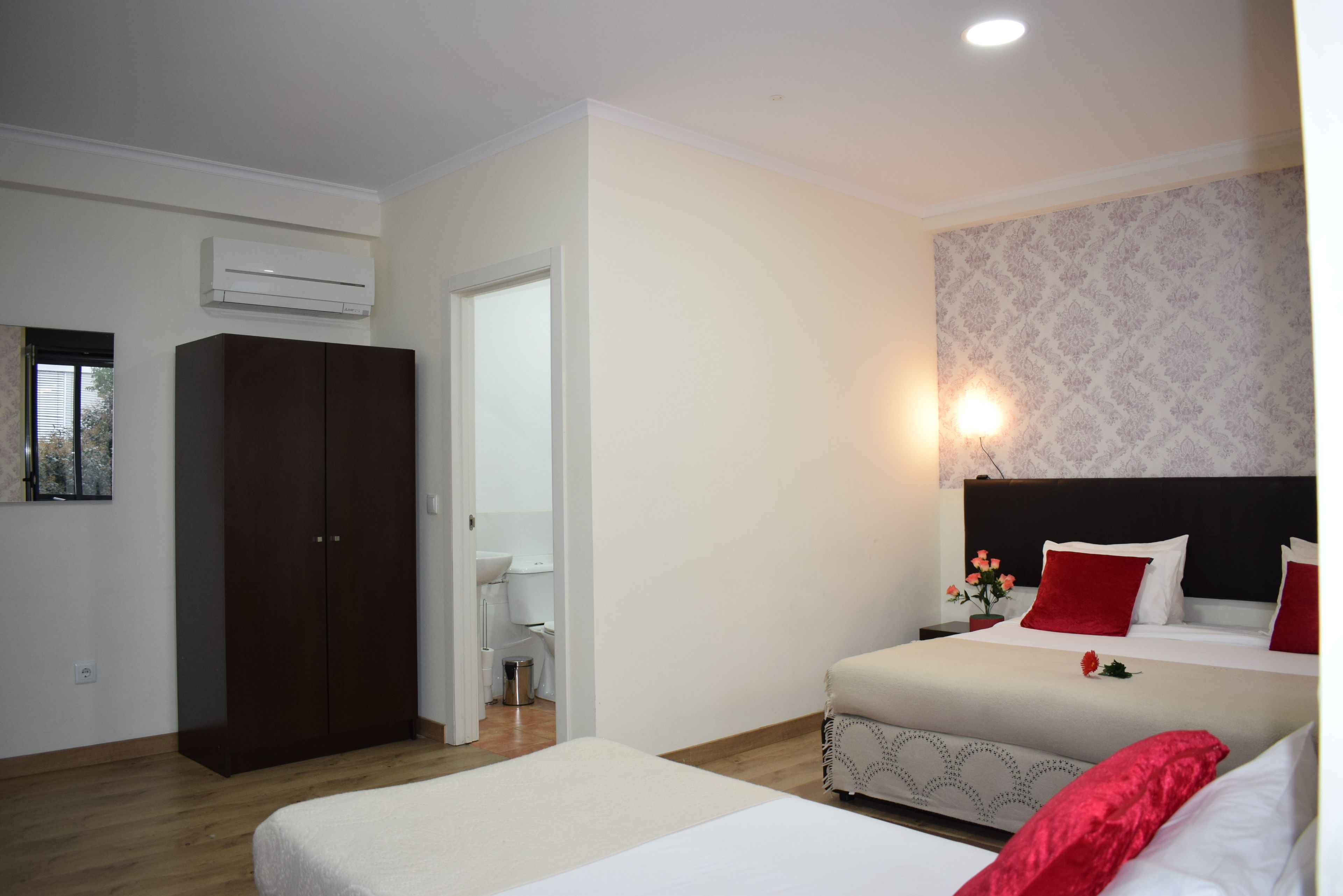 Une chambre d’hôtel comprenant un lit, une armoire, une salle de bain et un climatiseur fixé au mur.