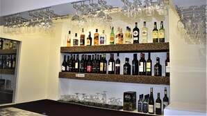 A bar area with shelves of liquor bottles and hanging wine glasses. - Universo Romântico Guesthouse & Spa (Lisbon)