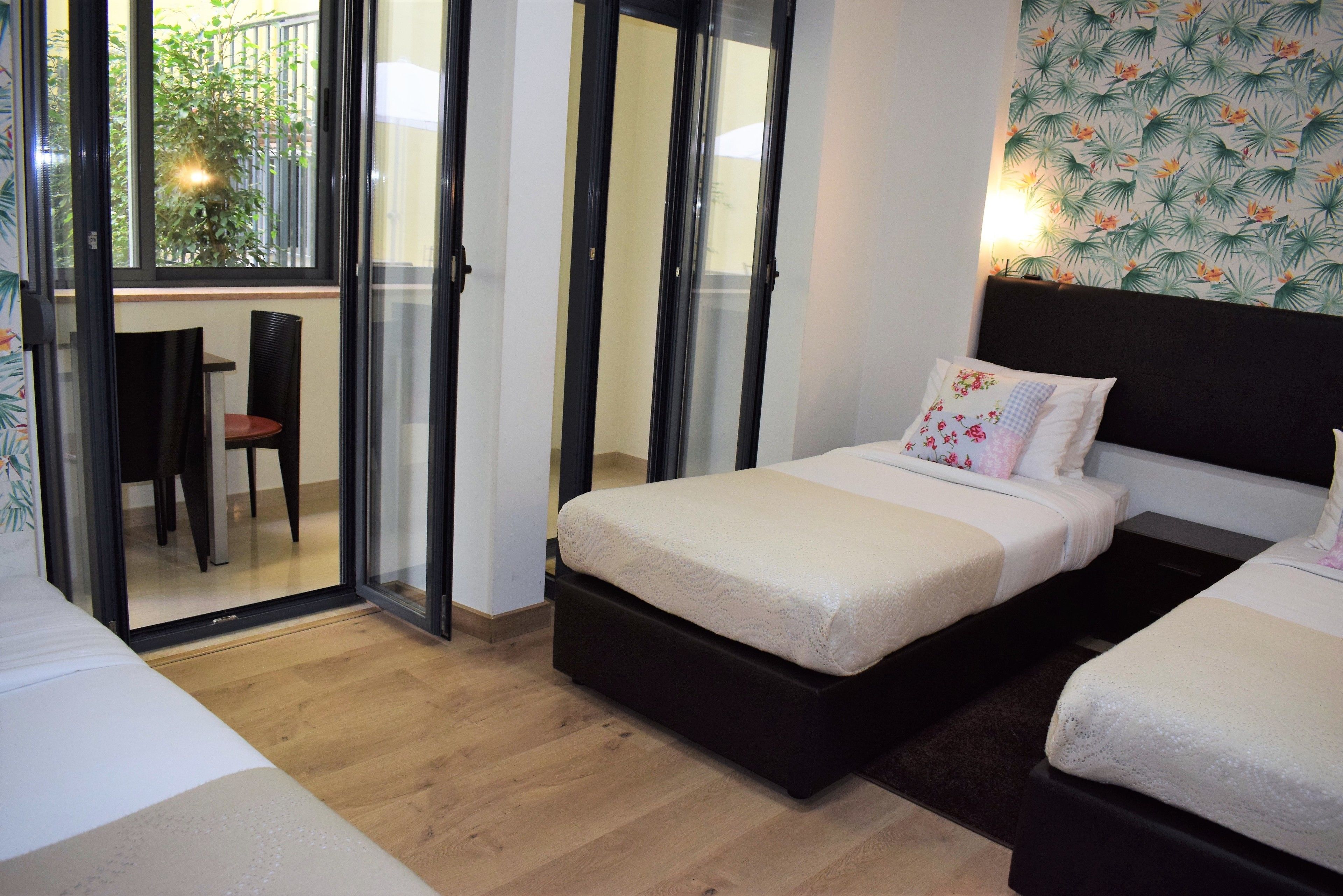 Un dormitorio con cama, una silla y un ventanal corredero que da a un balcón.