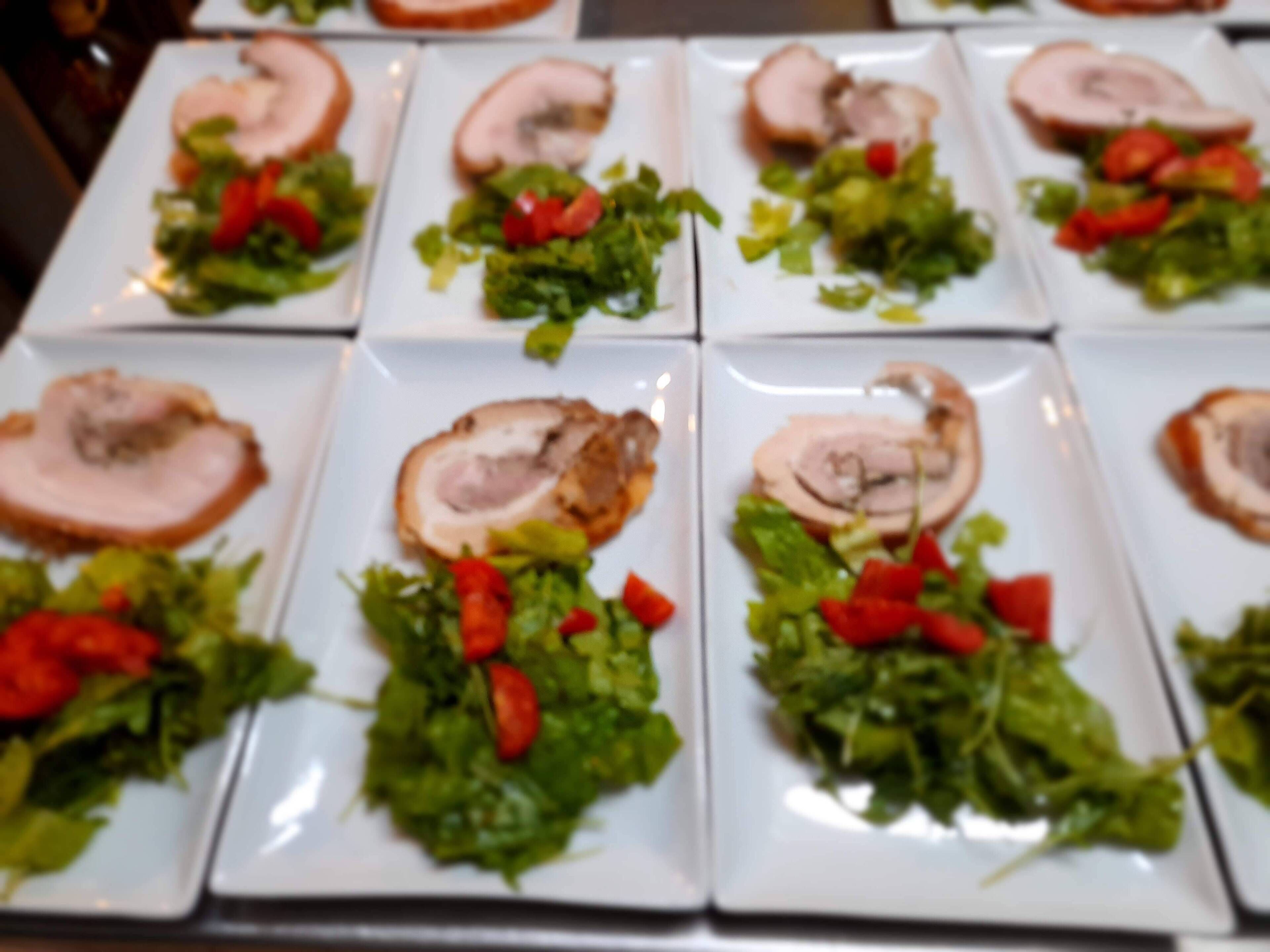 A row of square plates with sliced meat and salad.