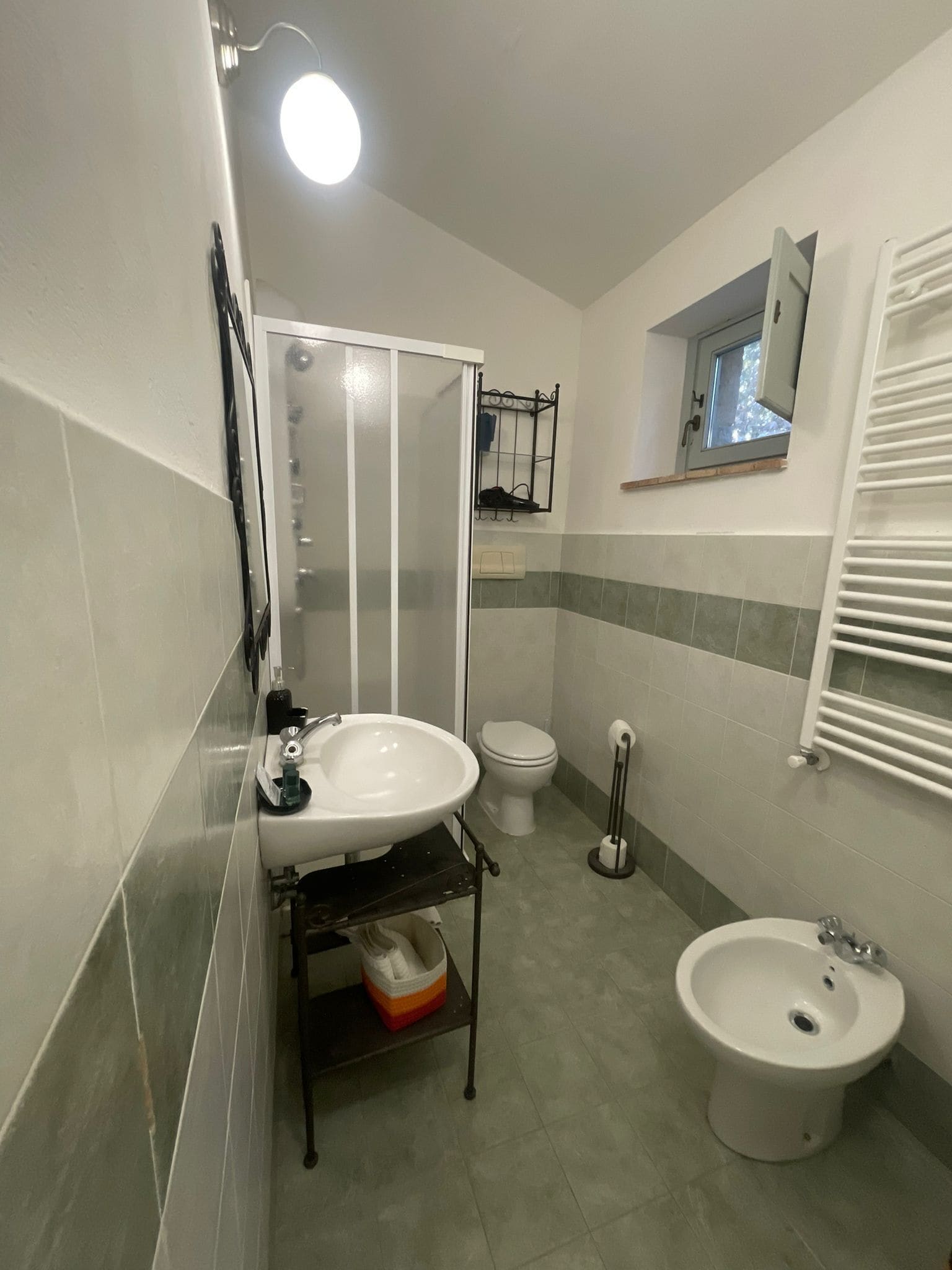 Uma casa de banho com lavatório, sanita, bidé e cabine de duche.