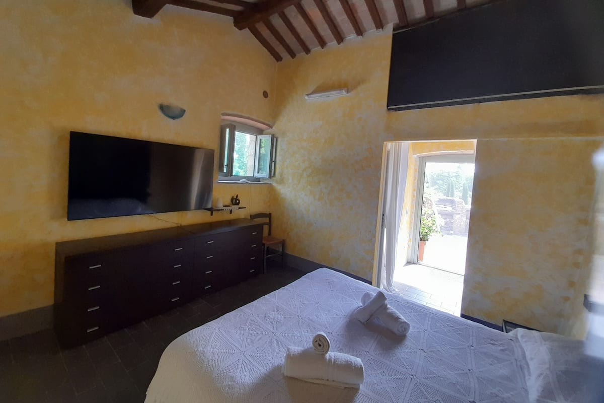 Une chambre à coucher avec un lit, une télévision, une commode et une fenêtre donnant sur un beau paysage.
