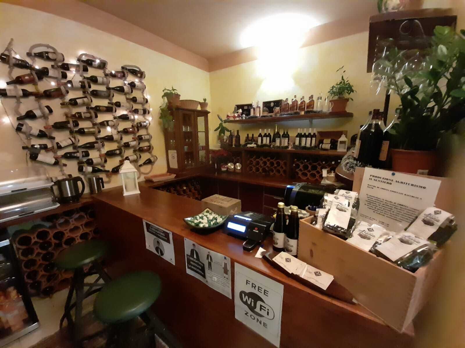 Ein Barbereich mit Weinkühler, Regalen voller Flaschen, einer Registrierkasse und einem Schild für eine kostenlose WLAN-Zone.