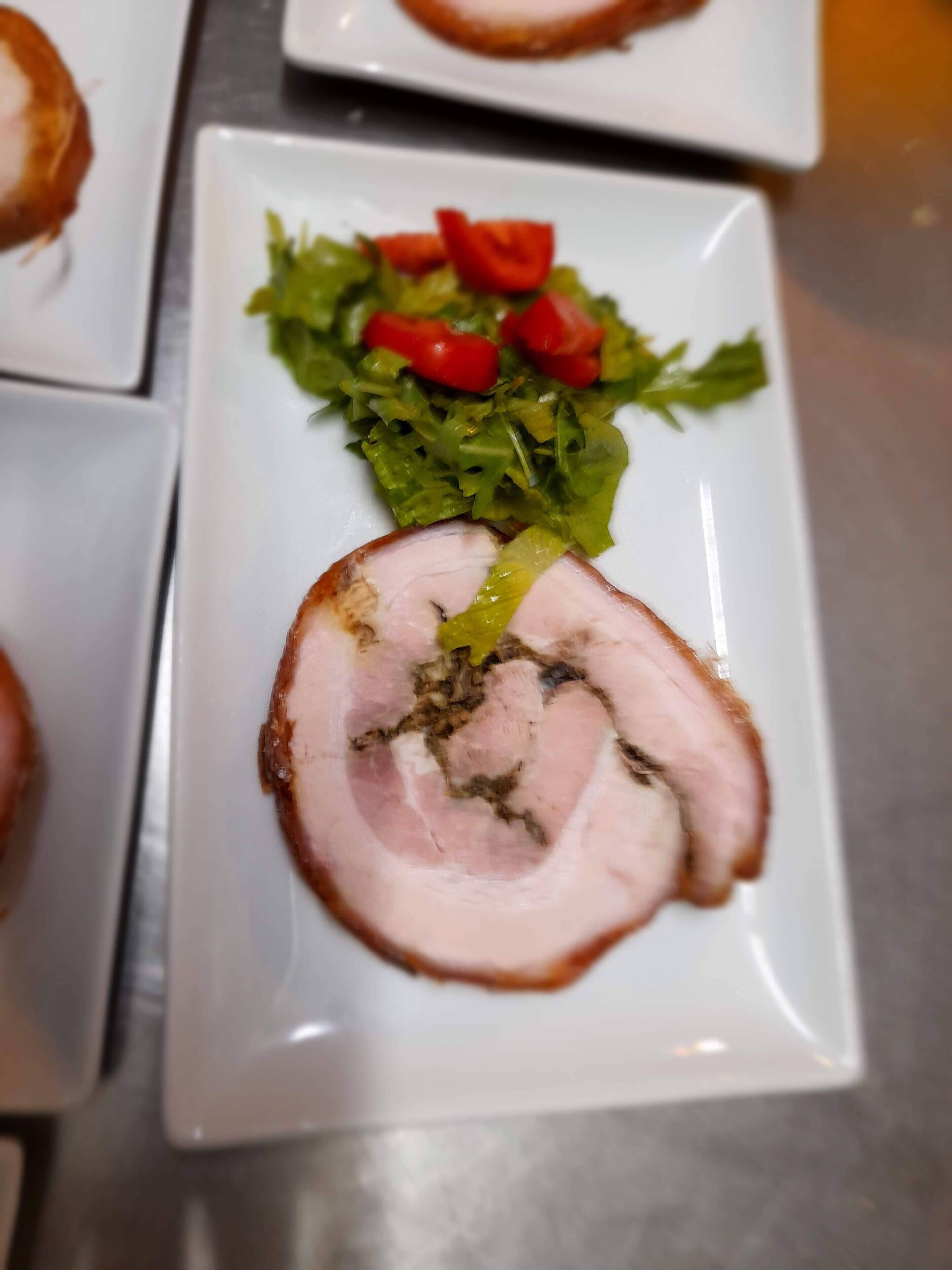 Een bord met plakjes vlees en een salade.