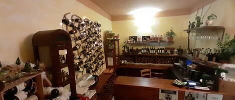 A bar area with a wine rack, shelves with bottles, and a counter with stools.