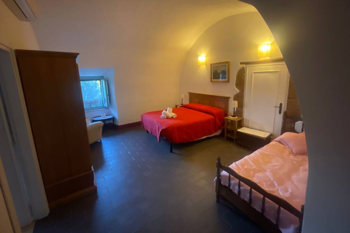 Une chambre d’hôtel avec deux lits, une armoire en bois, une petite table avec une chaise et une fenêtre.