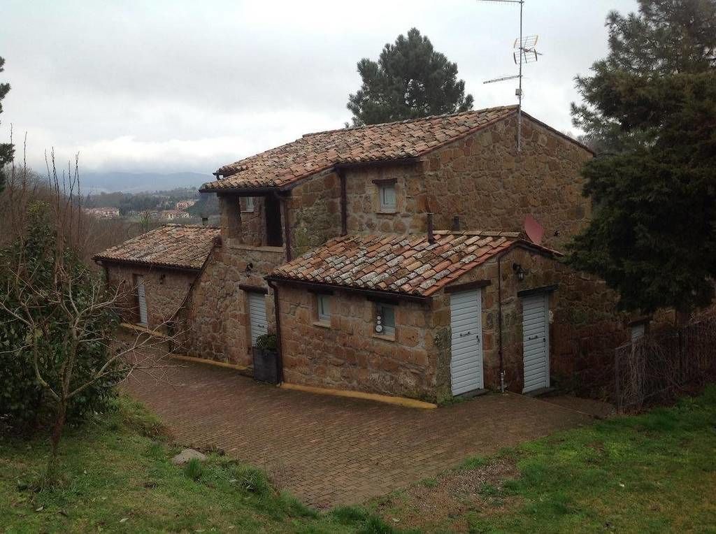 Ein Steinhaus mit Ziegeldach, zwei Garagentoren und einer Satellitenschüssel.