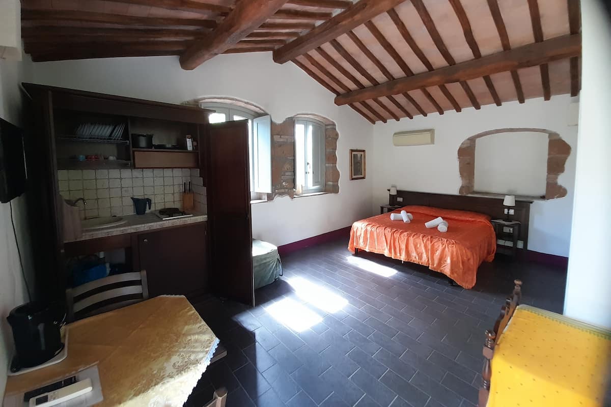 Une chambre à coucher avec un lit, une tête de lit en bois, une table de chevet, un miroir et une fenêtre.
