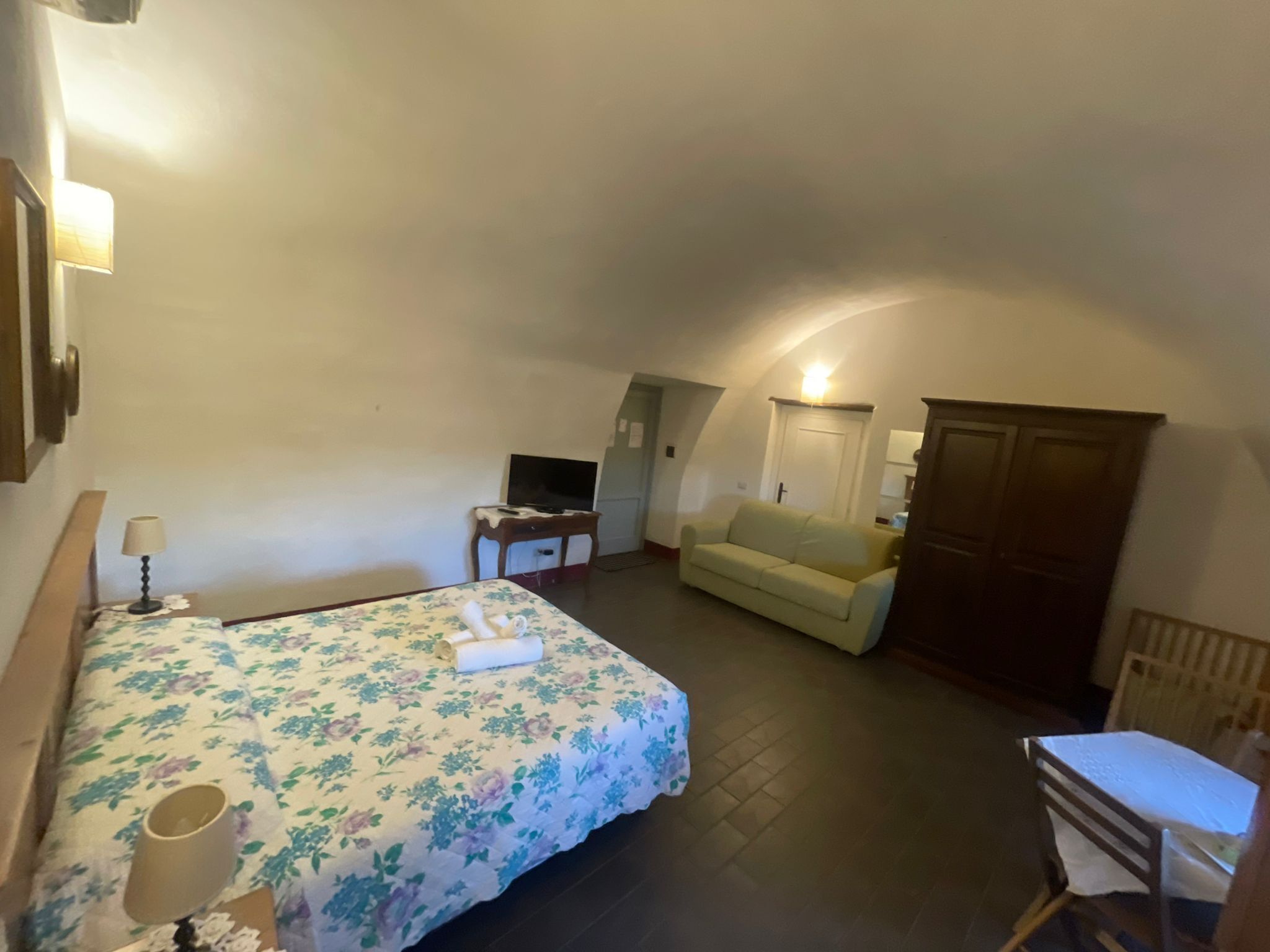 A small, cozy room with a bed, a sofa, a desk, and a wardrobe.