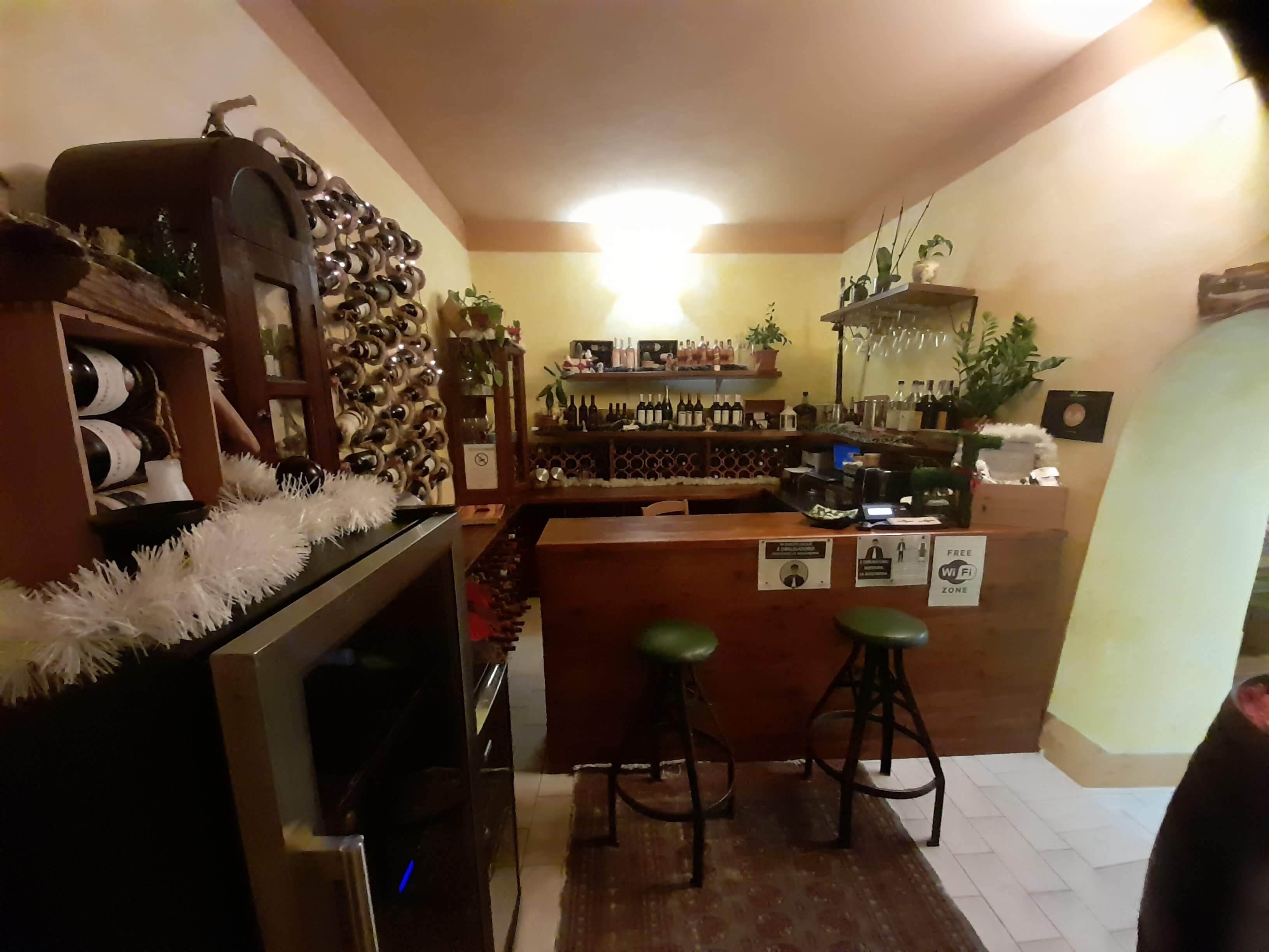 Zona de bar con una bodega, taburetes y una barra.