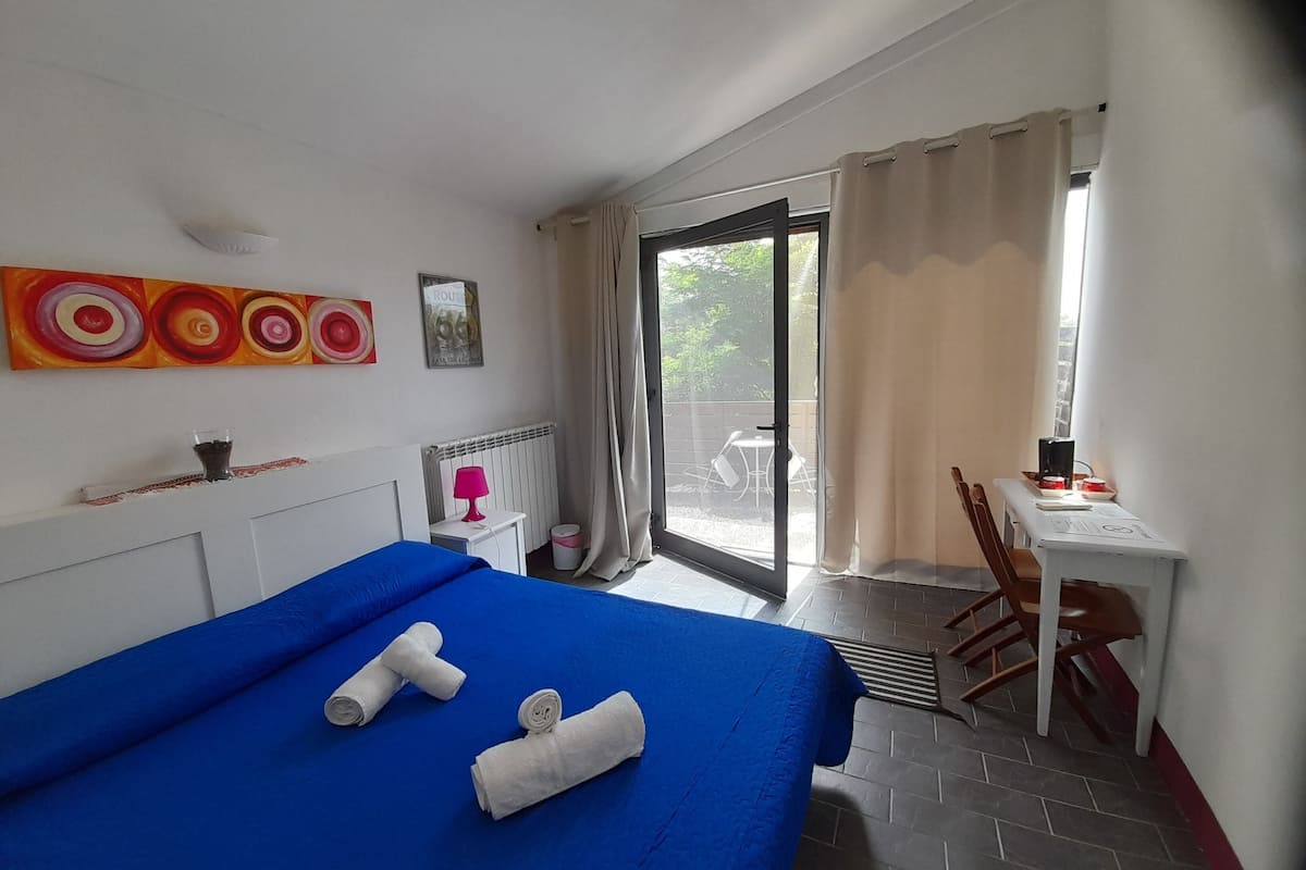 Une chambre d’hôtel comprenant un lit, un bureau, une chaise, un radiateur, une fenêtre avec des rideaux et une vue sur l’extérieur.
