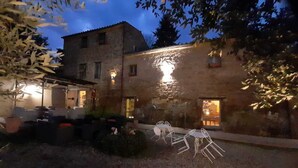 A stone building with a patio area, outdoor seating, and a small garden. - Agriturismo Il Sentiero (Acquapendente)