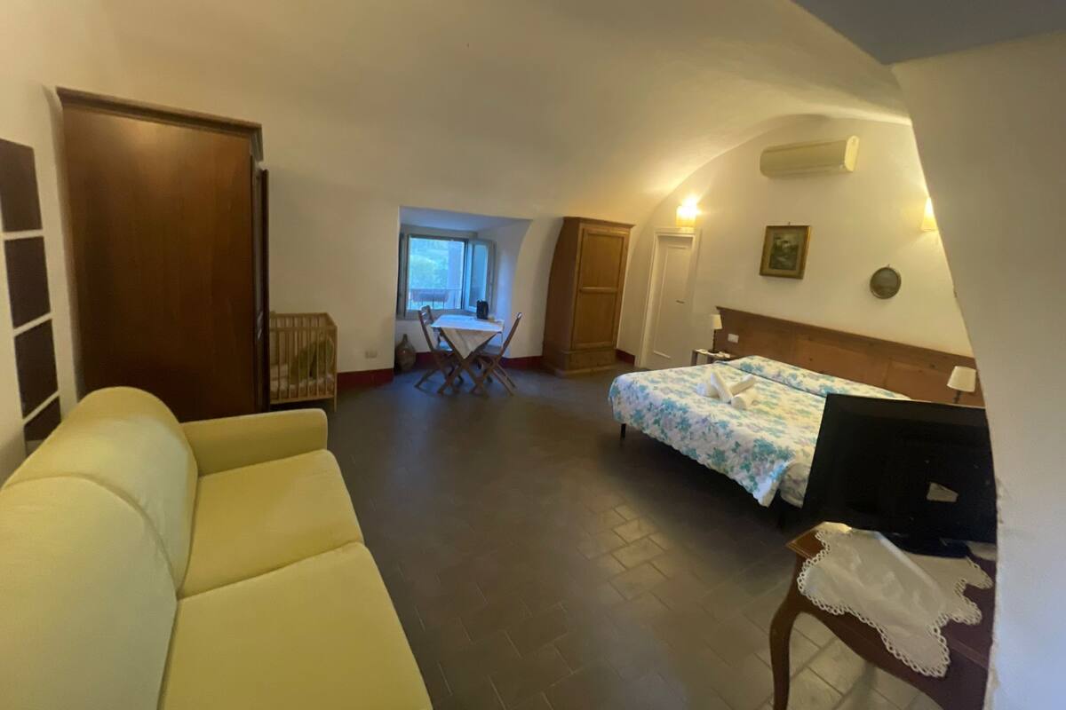 Une chambre d’hôtel comprenant un lit, un canapé, une table à manger avec des chaises, une armoire en bois et une fenêtre.