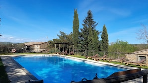 A swimming pool with lounge chairs and a stone building in the background. - Agriturismo Il Sentiero (Acquapendente)
