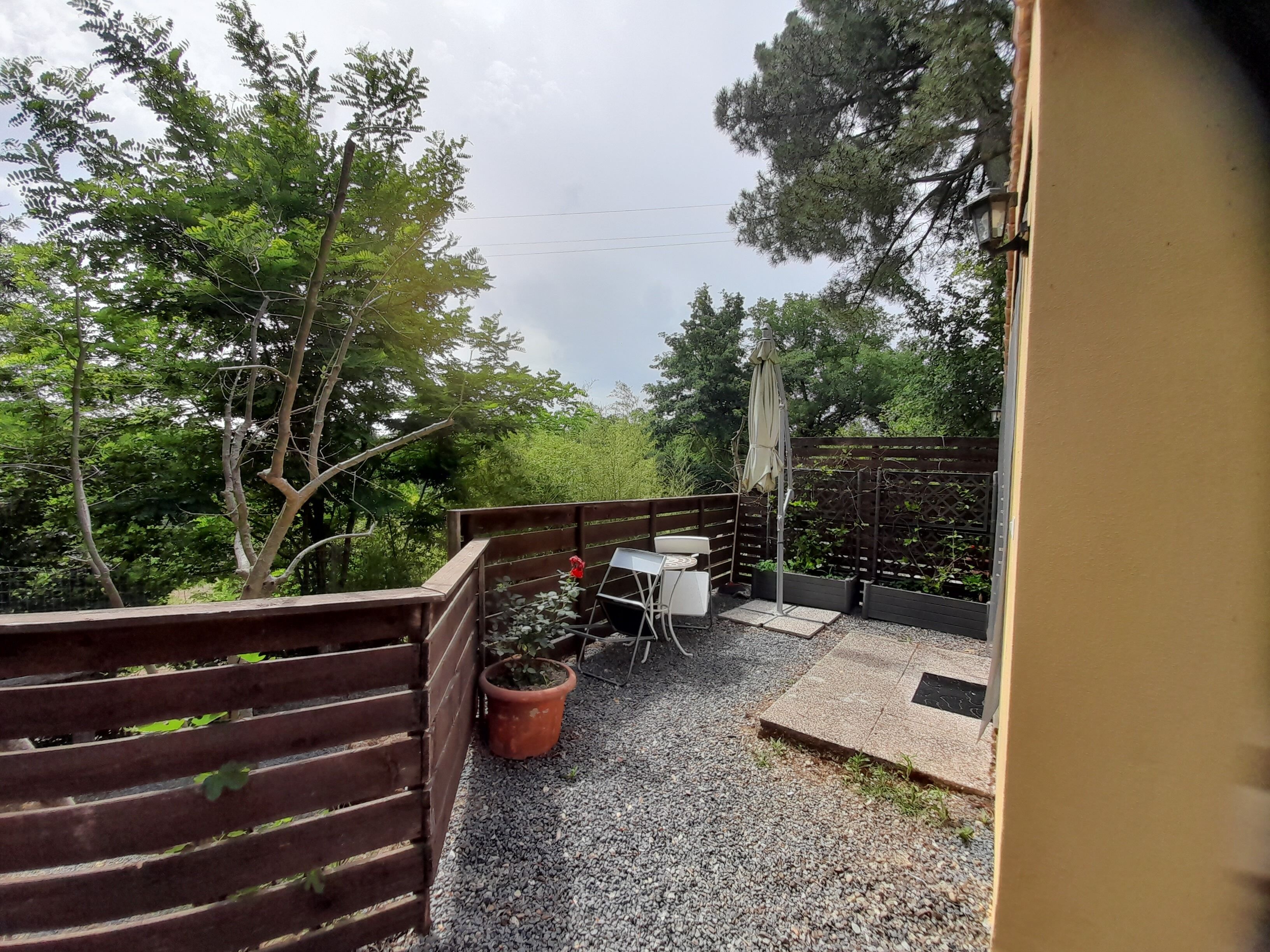 A patio area with a table and chairs, surrounded by a wooden fence and potted plants.