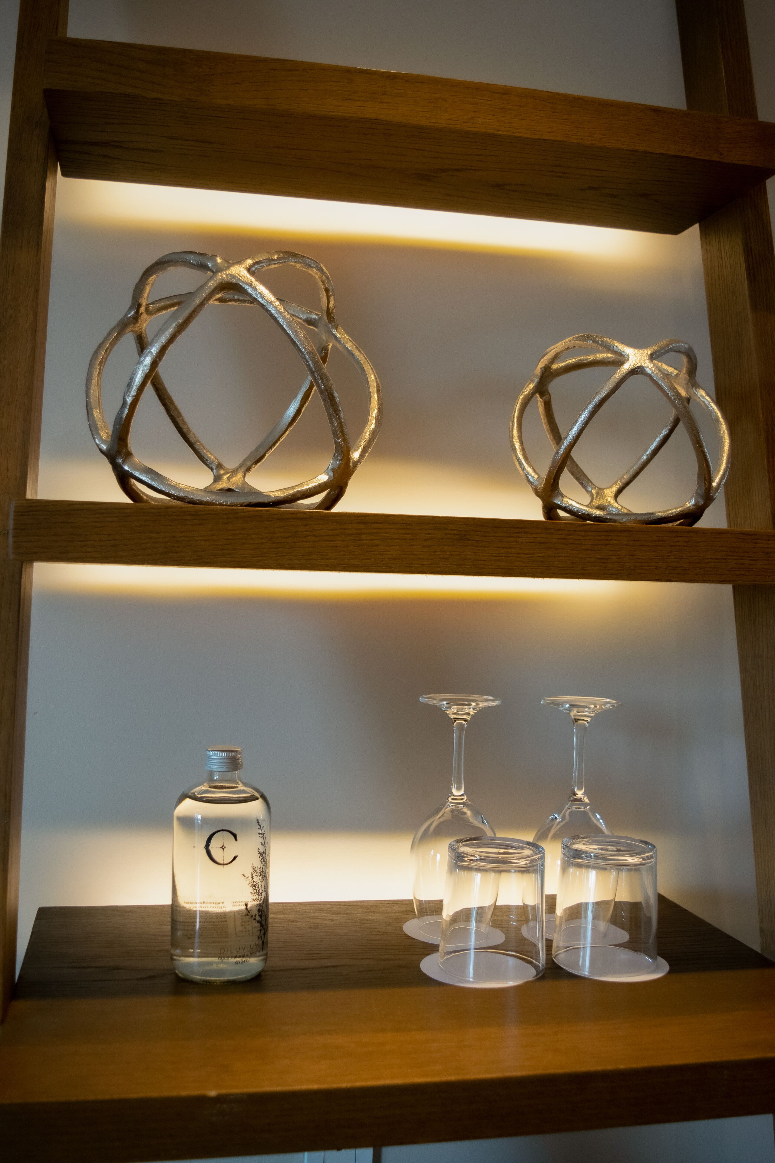 Une étagère ornée d’anneaux métalliques décoratifs et sur laquelle sont posés trois verres à vin.