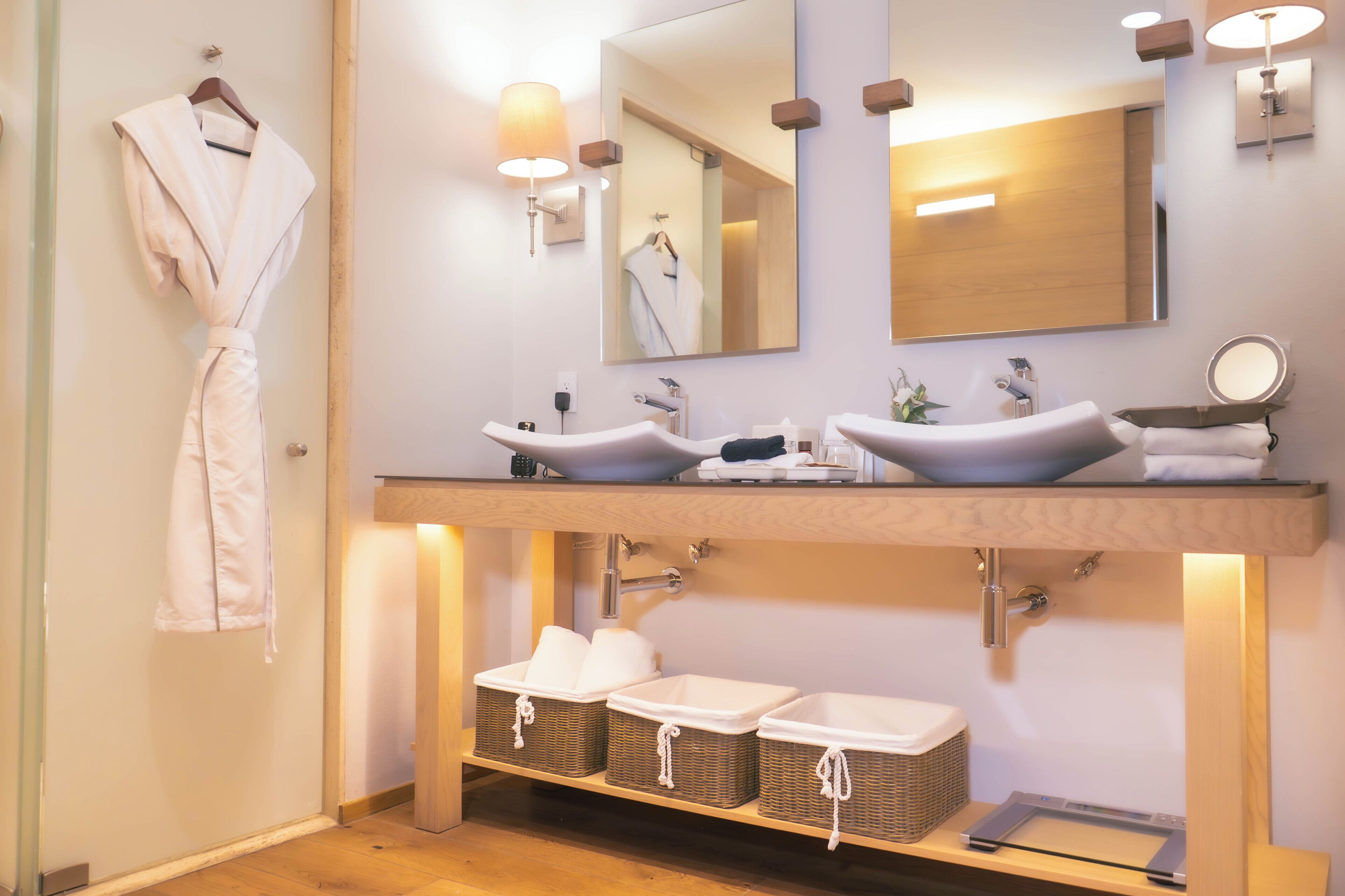 Um banheiro moderno com duas pias, um espelho grande e um roupão pendurado na parede.