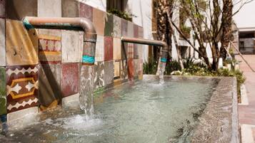 A water feature with a tiled wall and a metal pipe.
