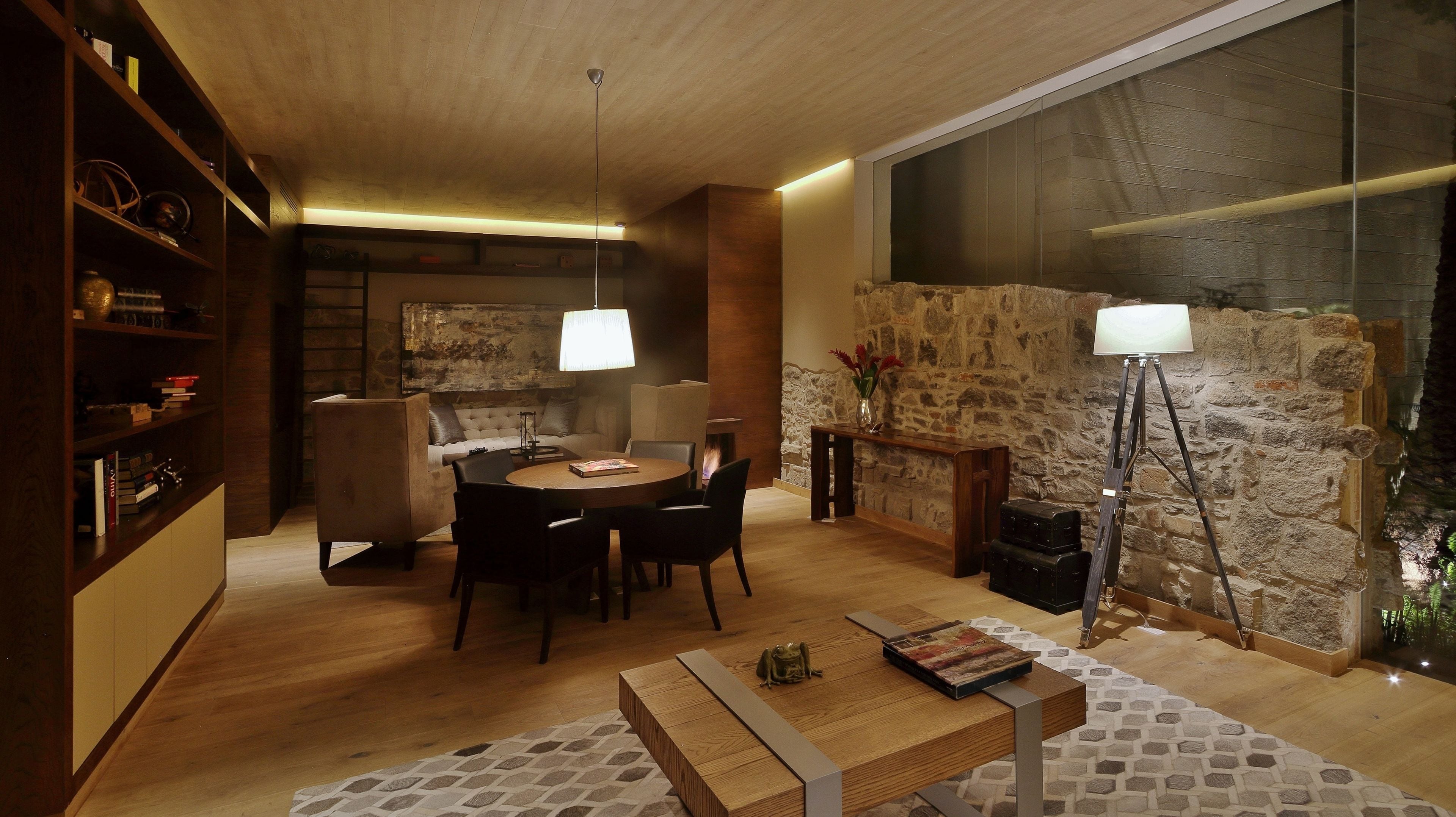 A cozy living room with a fireplace, a dining area, and a large stone wall.