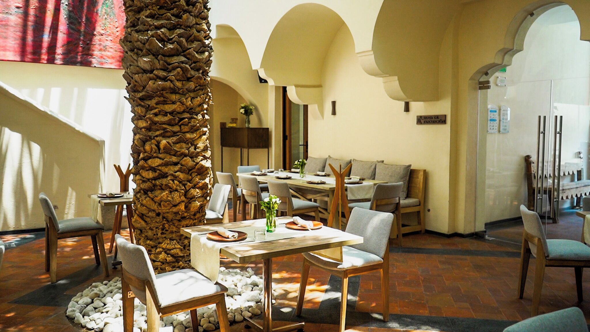 A restaurant with a stone pillar, tables, chairs, and a tiled floor.