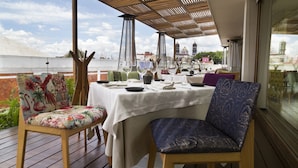 Een eetgedeelte met een tafel voor twee, met uitzicht op een pittoresk waterfront.
