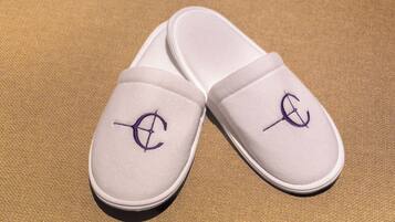 Een paar witte slippers met een paars logo op een gestructureerd oppervlak.