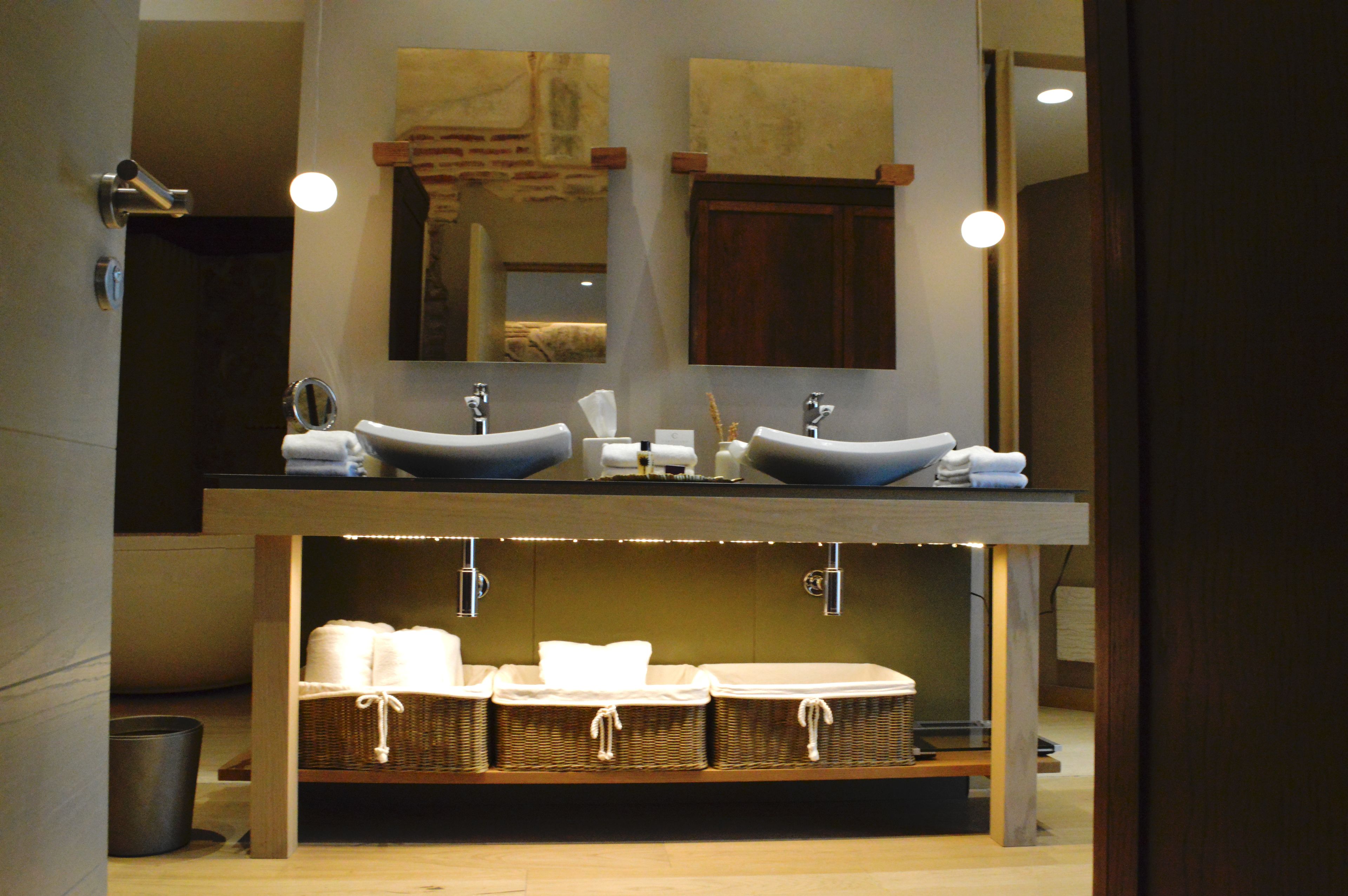 A bathroom with two sinks, a mirror, and a shelf with baskets.